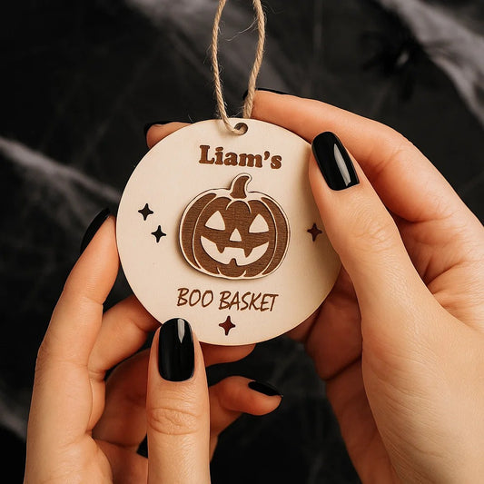 Personalised wooden Boo Basket tag with engraved name and pumpkin design held in hands